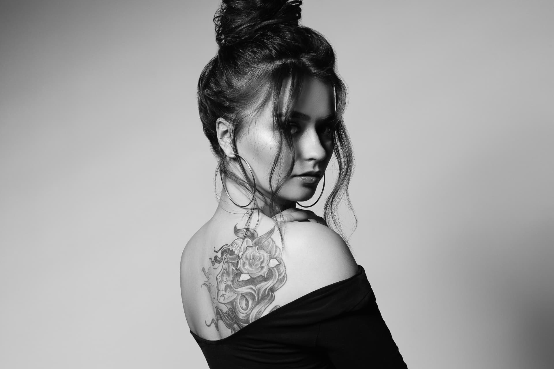 Portrait noir et blanc d'une cliente tatouée, épaule et dos visibles